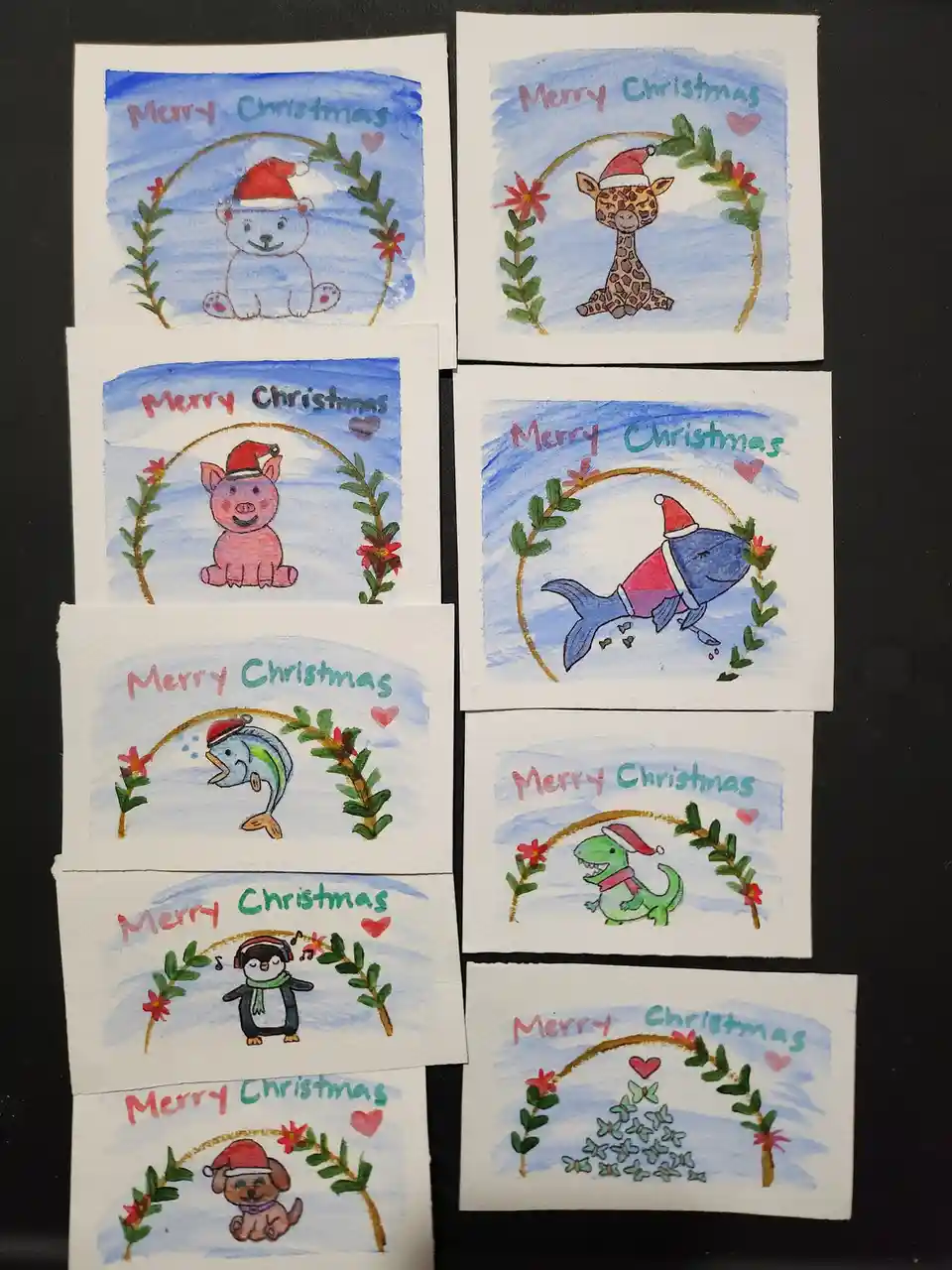 Seven hand-drawn Christmas cards are arranged on a dark surface, each featuring a different animal or object wearing a Santa…