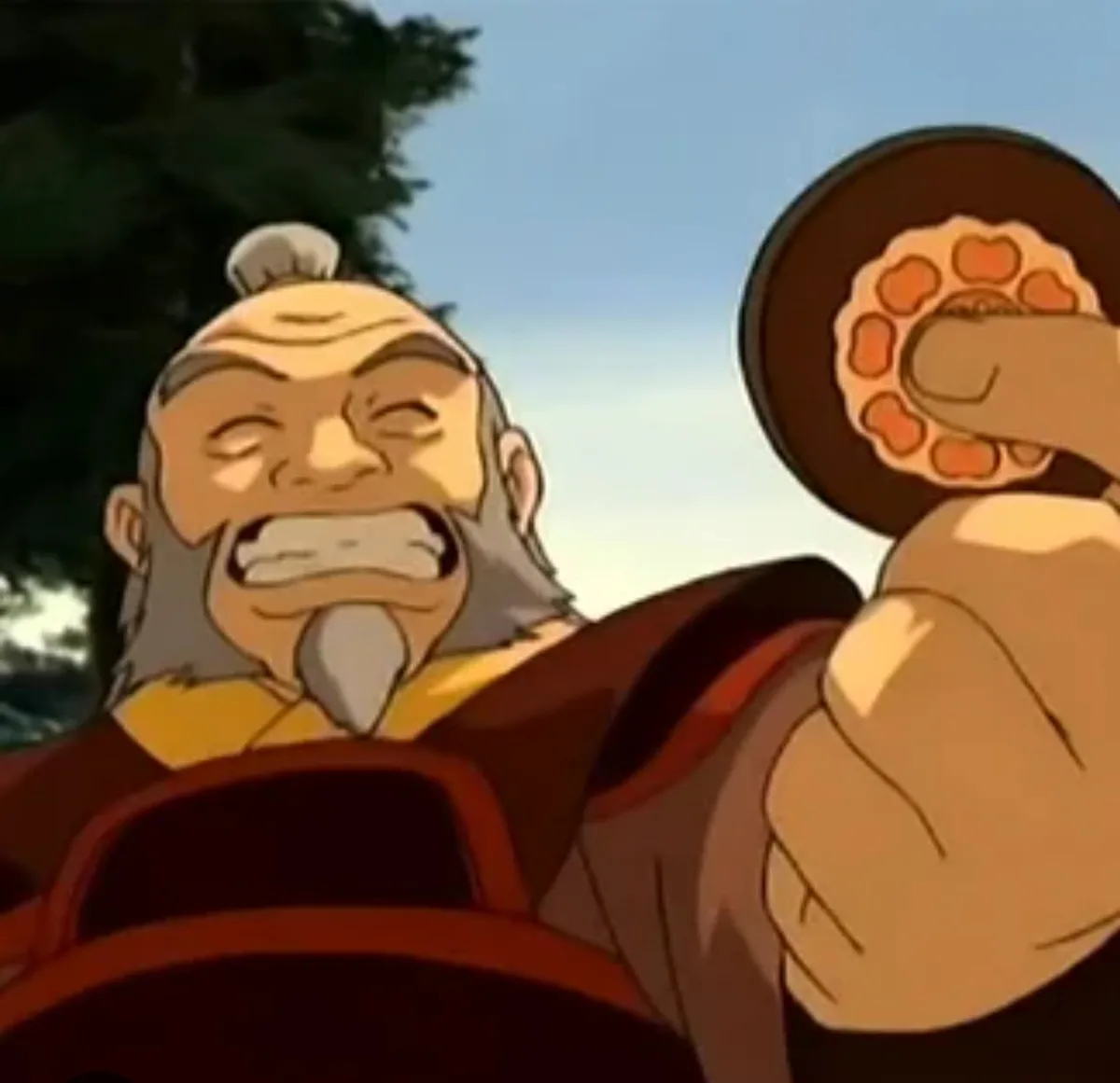 An animated elderly man with a white beard and topknot, wearing red and yellow robes, grimaces with his eyes closed and…