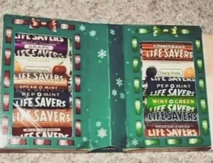 An open, green, Christmas-themed Life Savers candy box displays multiple flavor labels on both sides, including Grape…