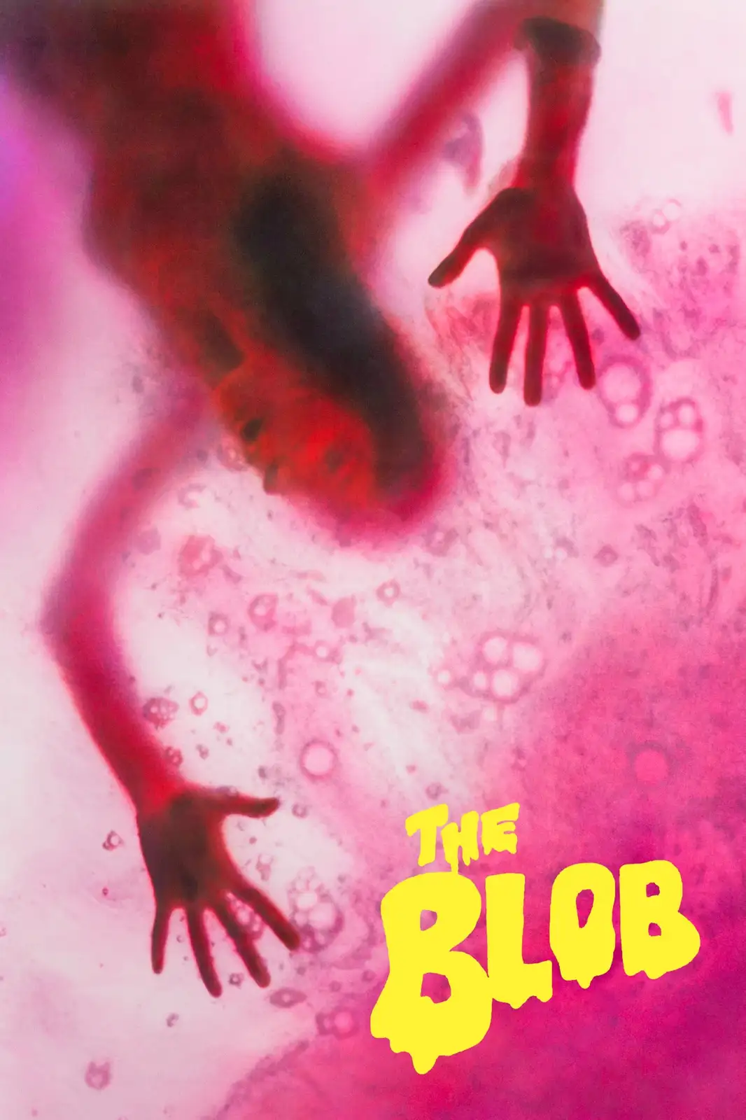 A blurry, red-tinged image shows a human figure seemingly submerged or encased in a pink, gelatinous, bubbly substance, with…