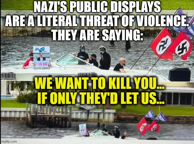 A boat with several people on it, some wearing black clothing and masks, flying Nazi flags, and holding a sign with a photo…