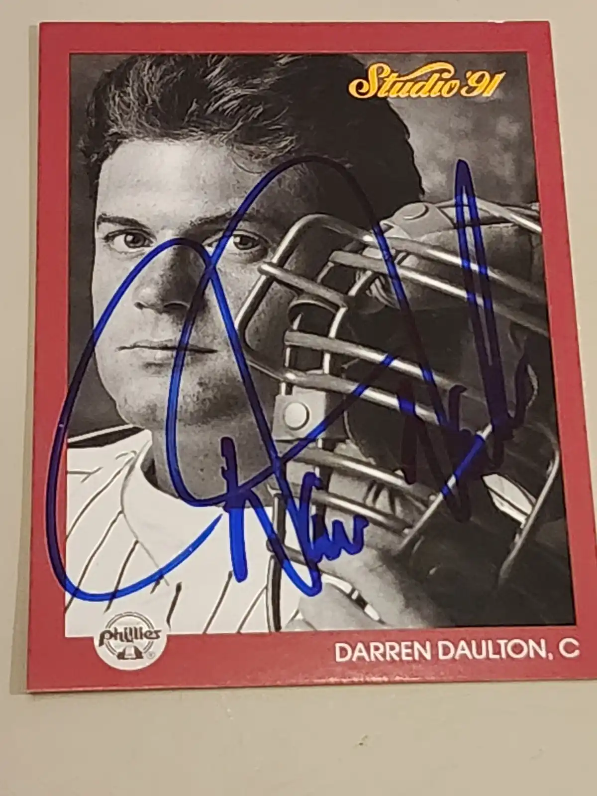 A vintage 1991 Studio '91 baseball card of Darren Daulton, catcher for the Phillies, features a black-and-white photo of him…