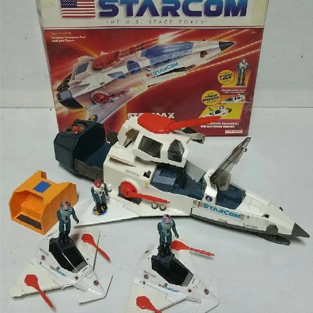 A vintage Starcom toy set is displayed with its box, featuring a large white and blue spaceship with red accents, two…