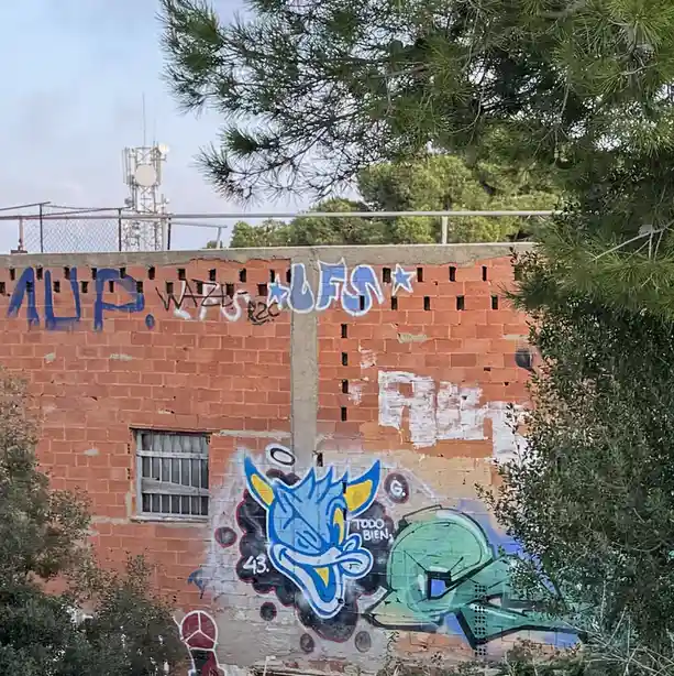 A brick wall covered in graffiti, featuring a blue cartoon character with yellow ears and the text 'TODO BIEN, 43.' next to…