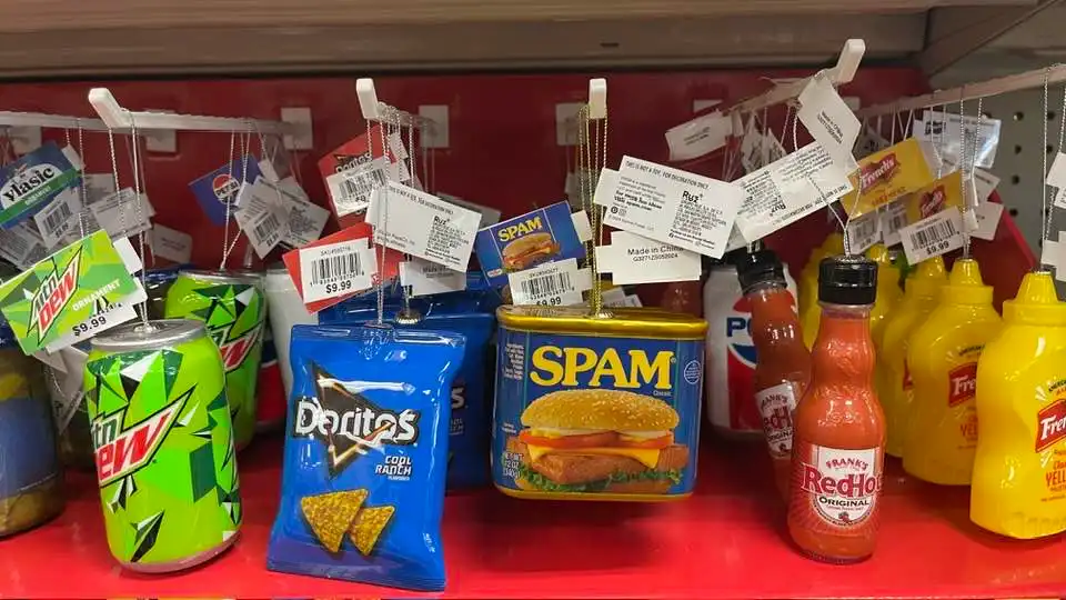 A store shelf displays various snack and condiment items including Mountain Dew, Doritos, a can of SPAM, and hot sauce…