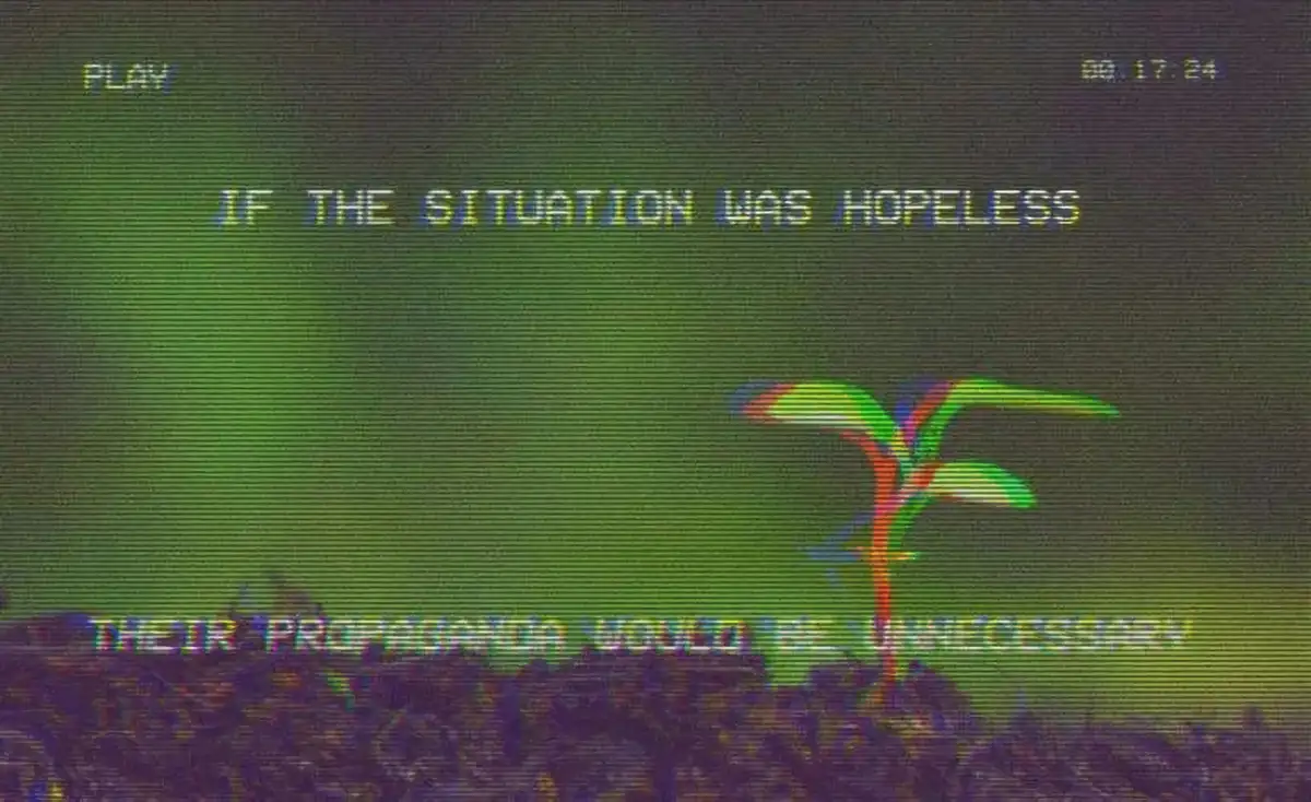 A grainy, green-tinted image resembling old VHS or CRT screen footage shows a small, colorful plant sprouting from dark…