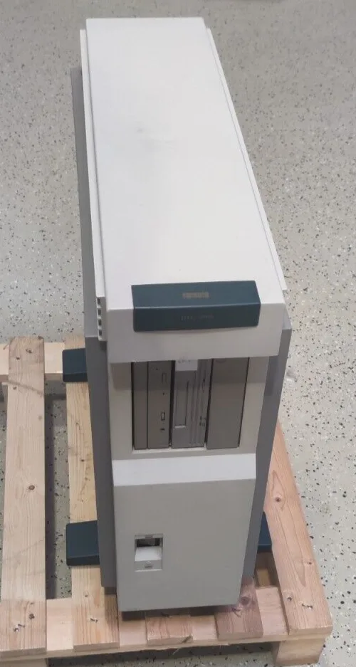 a large, beige, tower-style computer with a black panel labeled 'TANDY' sits upright on a wooden pallet. The machine has…