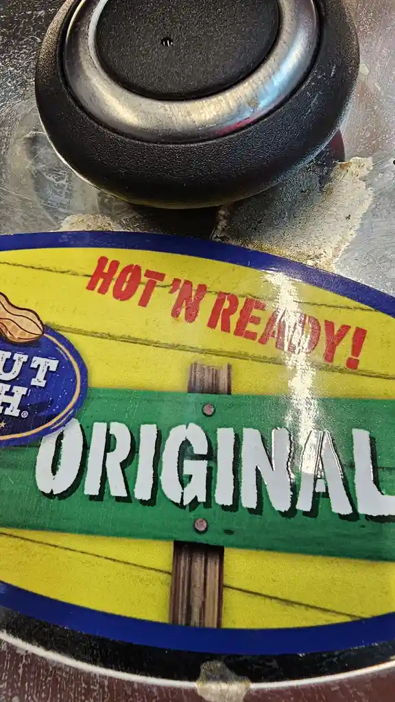 A close-up of a worn peanut butter jar lid showing the brand name 'Jif' partially visible, with the text 'HOT 'N READY!' in…