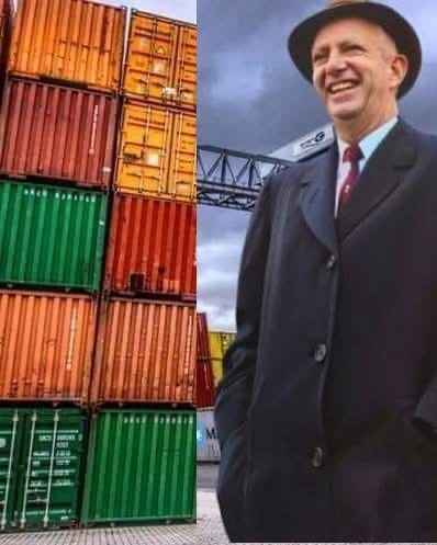 A split image shows a man in a dark suit, red tie, and fedora smiling broadly on the right, standing beside a stack of…