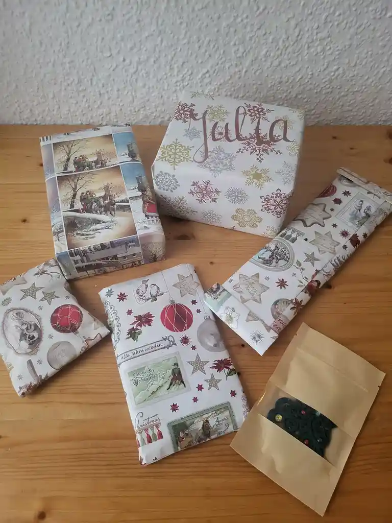 Several Christmas-themed gift packages wrapped in festive paper with snowflakes, ornaments, and holiday scenes sit on a…