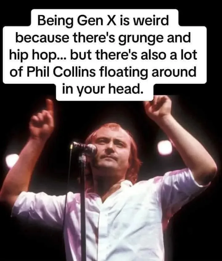 A photo of Phil Collins performing on stage with arms raised, wearing a light-colored shirt, standing before a microphone. A…