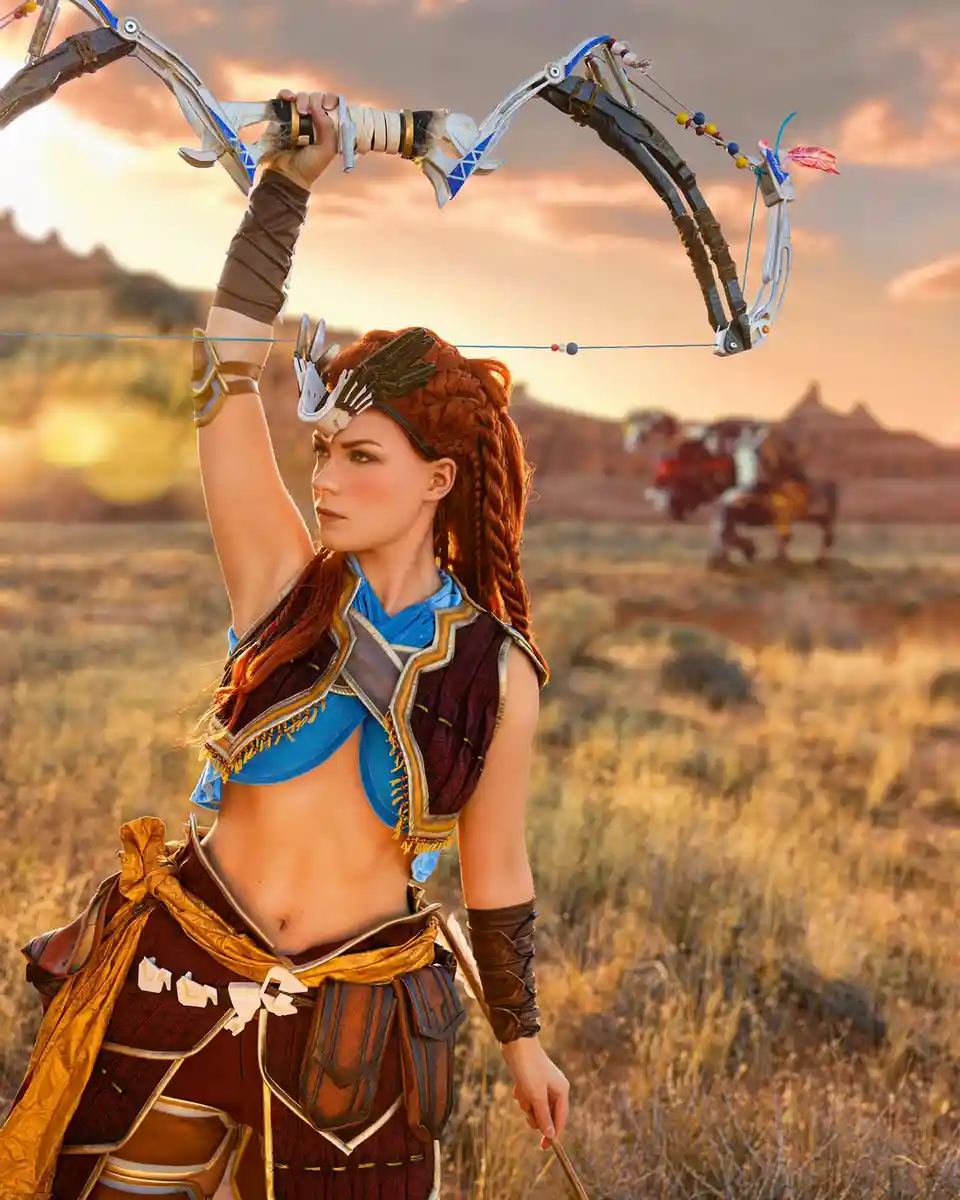 A woman in fantasy warrior attire, with red braided hair and a blue and brown outfit, holds a large, ornate…