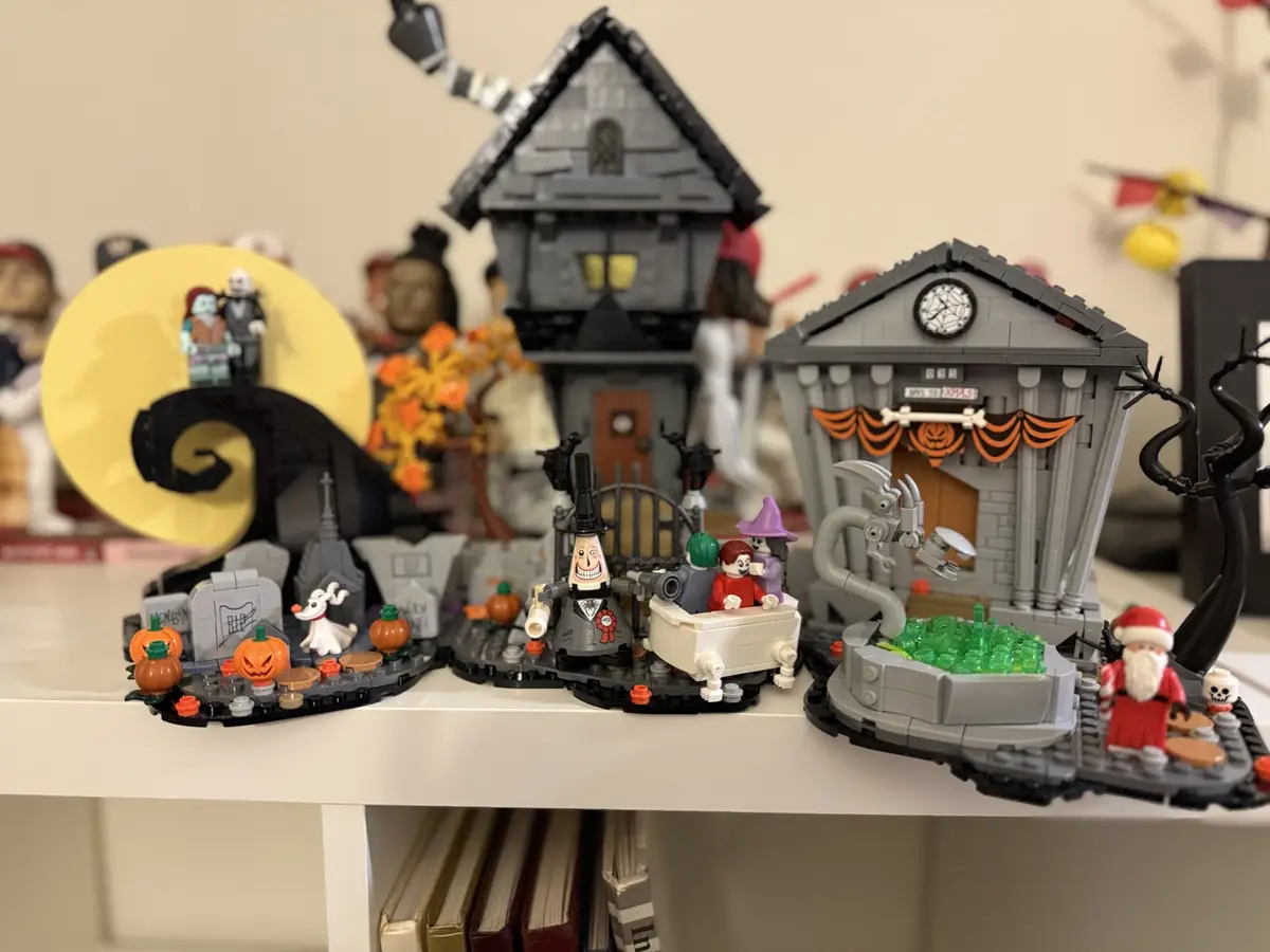 A LEGO diorama of the Halloween Town from 'The Nightmare Before Christmas' is displayed on a white shelf, featuring iconic…