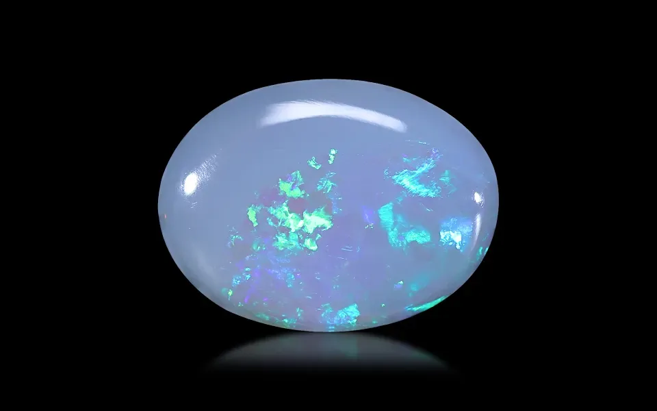 a smooth, oval-shaped opal gemstone with a milky white base and vibrant flashes of blue and green iridescence, set against a…