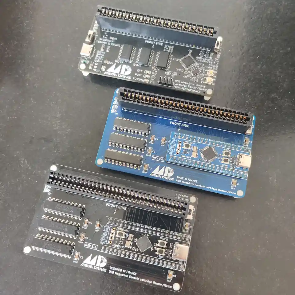 Three different revision boards for a USB Mega Drive Genesis cartridge reader/writer are shown, labeled REV 1.1, REV 2.0…