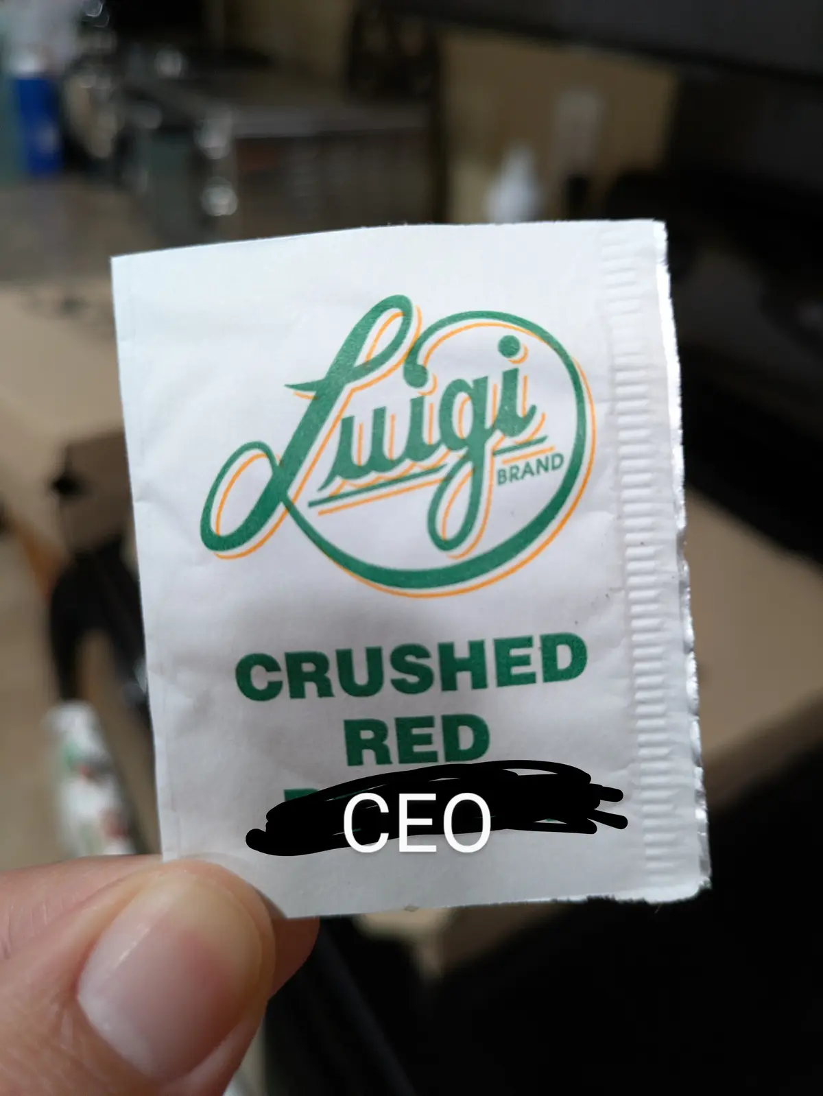 A close-up photo shows a hand holding a small white seasoning packet labeled 'Luigi Brand CRUSHED RED' with the word…