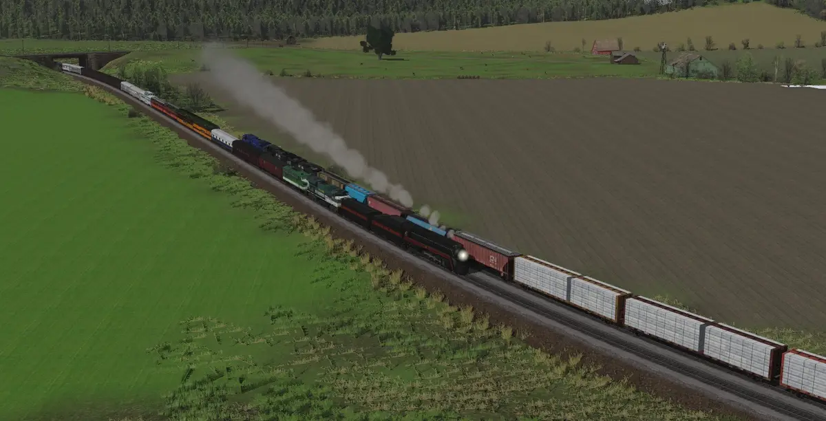 A long, colorful train with multiple locomotives and freight cars travels through a rural landscape with green fields and…