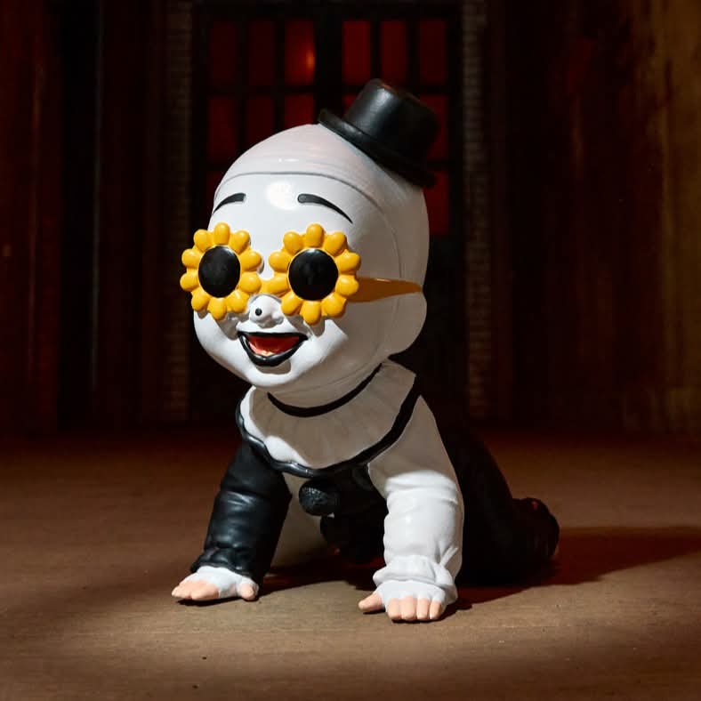 A white, stylized baby figurine wearing a black top hat, black leather pants, and oversized yellow sunflower glasses with…