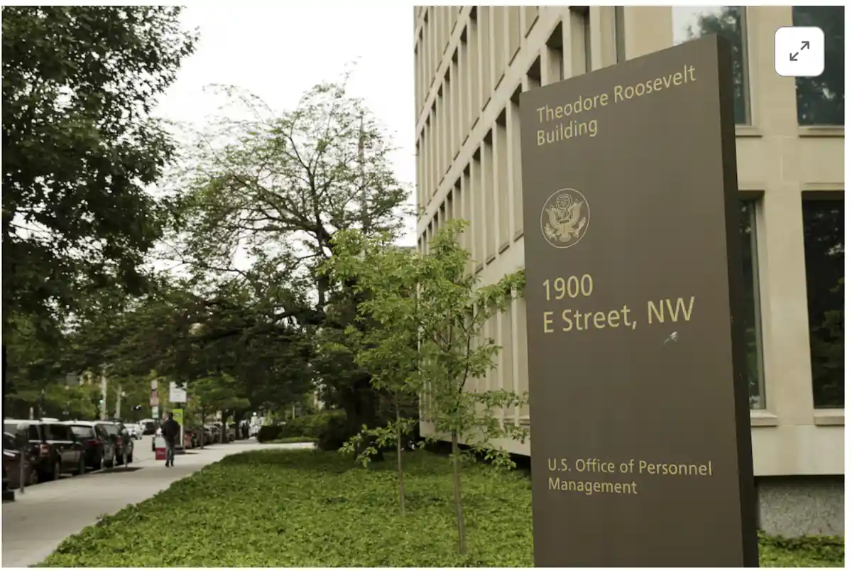 A photo of a brown sign for the Theodore Roosevelt Building at 1900 E Street, NW, which houses the U.S. Office of Personnel…