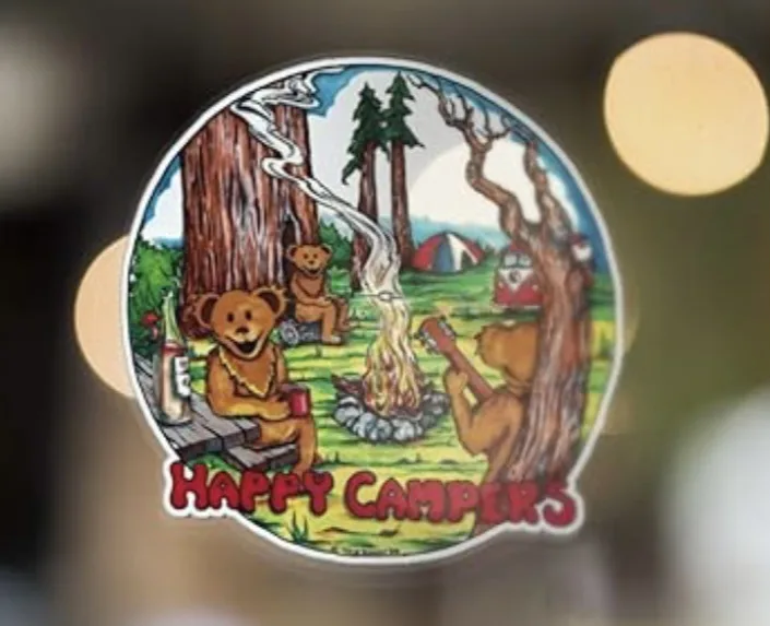 A circular sticker depicts three cartoon bears enjoying a campfire in a forest, with one bear playing a guitar, another…