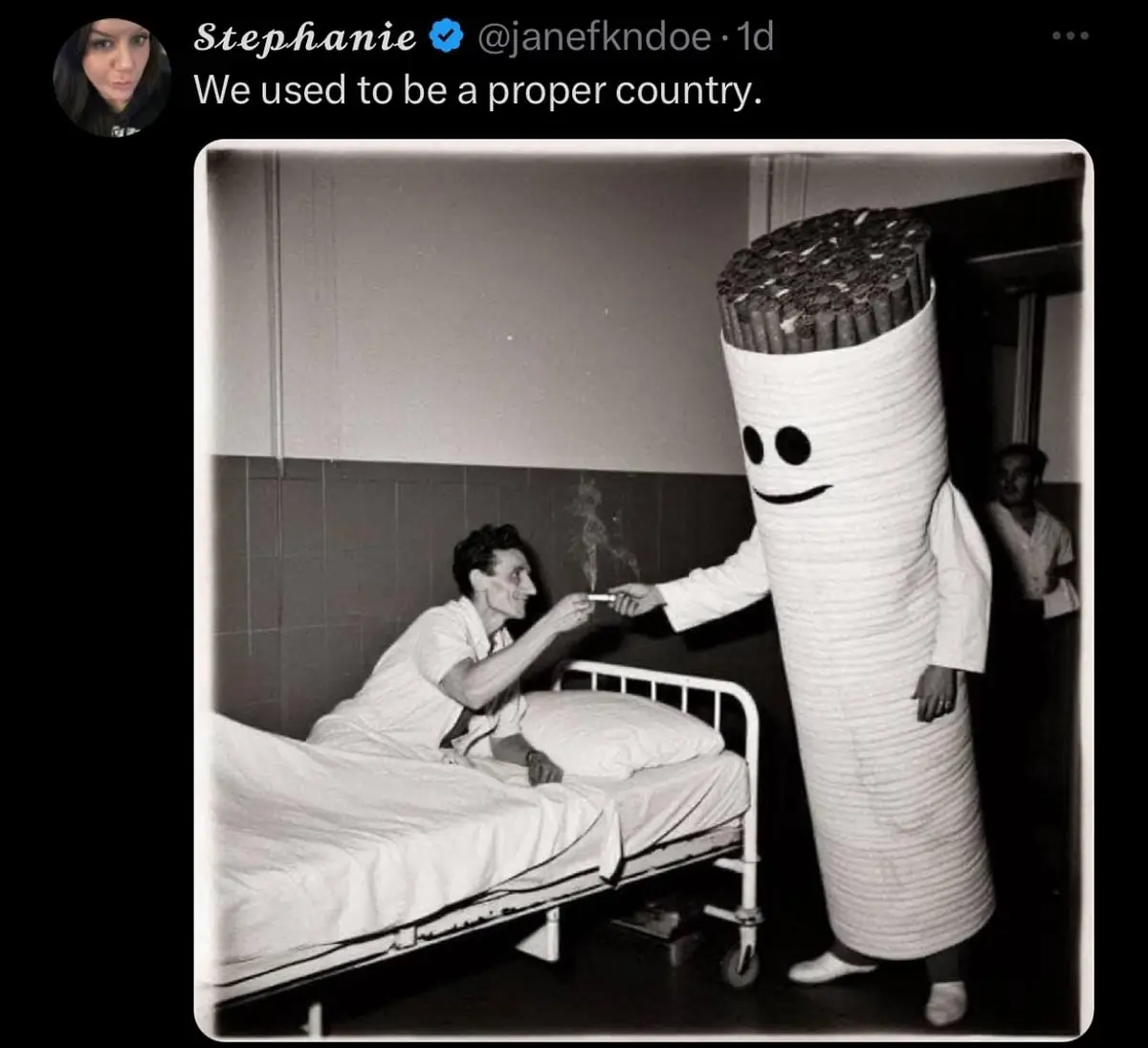 A black-and-white photo shows a man in a hospital bed smiling as he receives a cigarette from a person in a large, smiling…