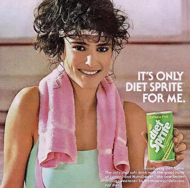 A woman with curly hair and a pink towel around her neck smiles while holding a green can of Diet Sprite. The text overlay…