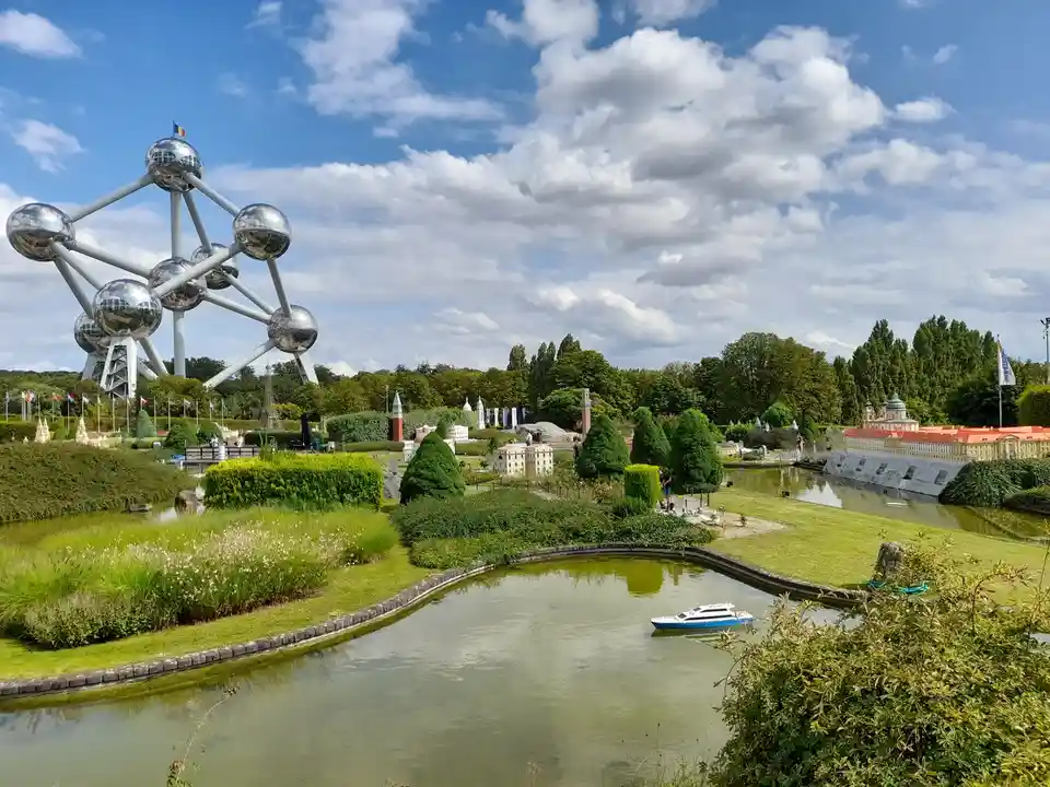 A scenic view of a miniature park with tiny scaled-down buildings and landscapes, featuring a large, real-life metallic…