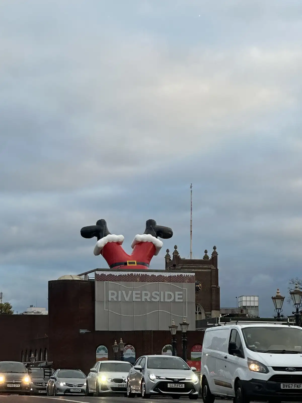 A large inflatable Santa Claus decoration, showing only his red pants with white trim and black boots, is perched atop a…