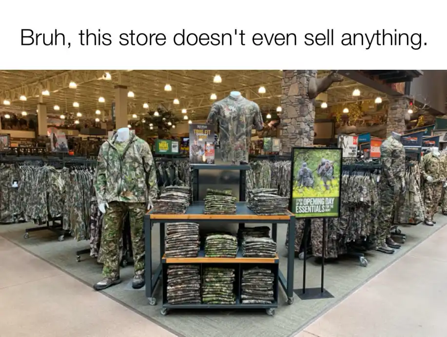 An indoor retail store aisle filled with racks and mannequins dressed in camouflage clothing, with shelves stacked with…