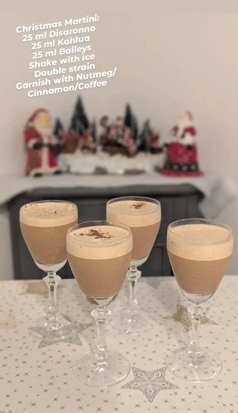Four stemmed glasses filled with a creamy, layered brown cocktail, garnished with a sprinkle of spice, sit on a…