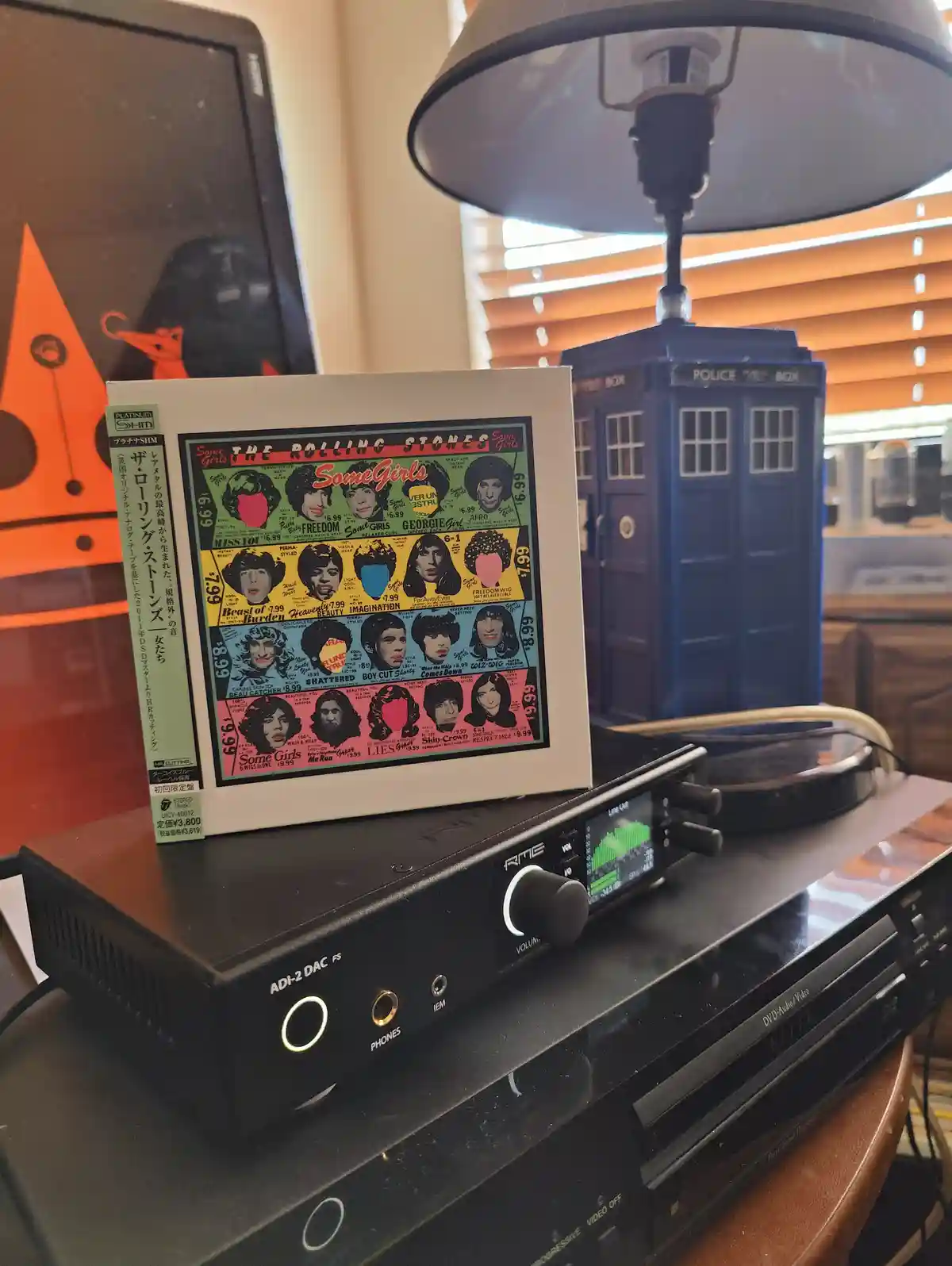 A Rolling Stones 'Some Girls' album cover, designed to look like a wig catalog with prices, sits on a high-end audio setup…