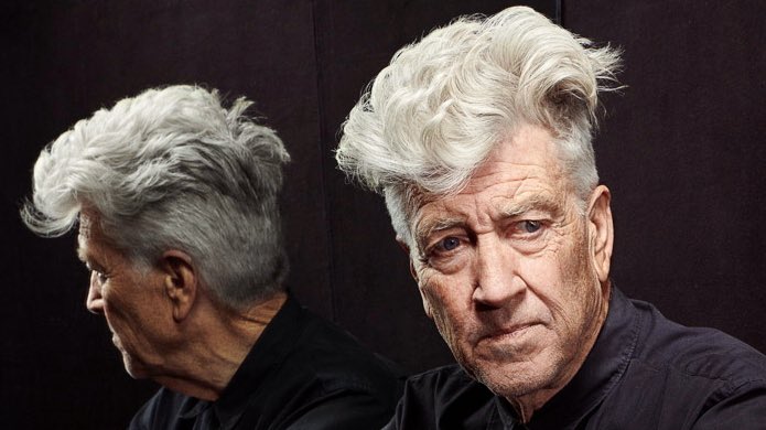 An older man with wild white hair is shown in profile and facing forward, both images superimposed. He wears a dark shirt…