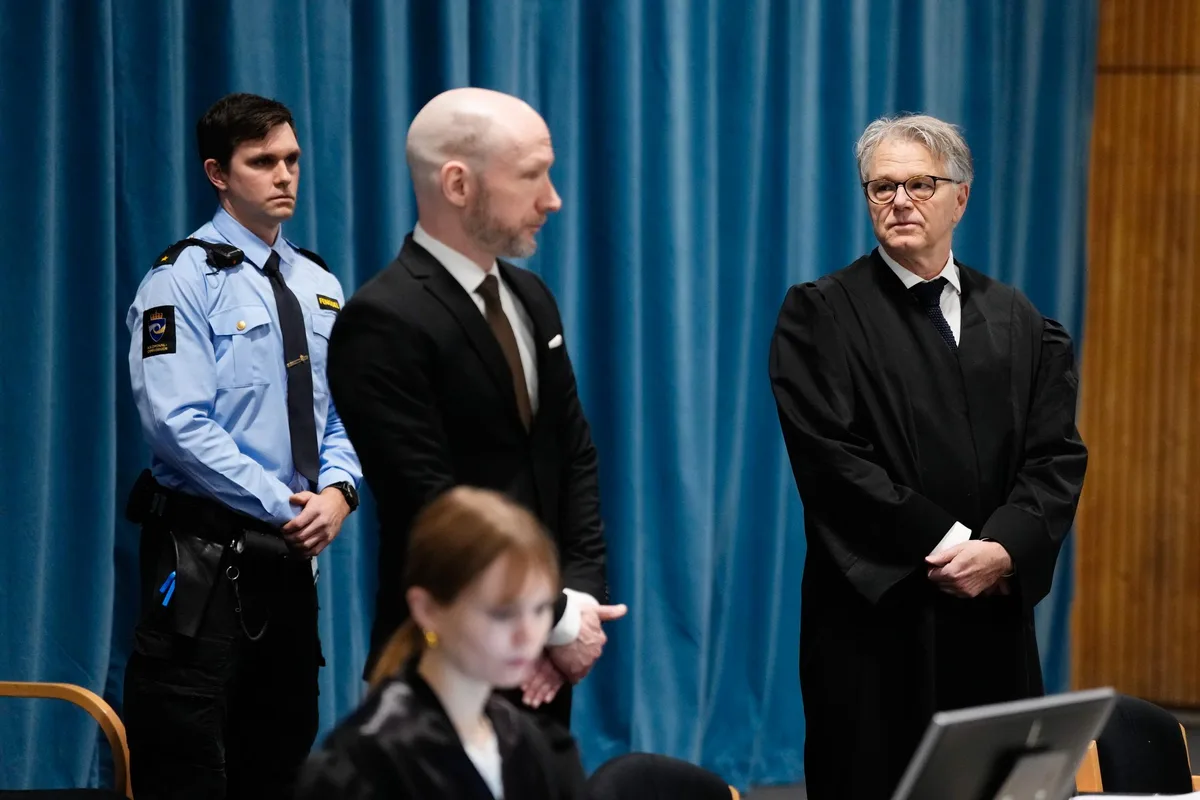 A man in a black suit stands between a police officer in a light blue uniform and a judge in a black robe, all in a…