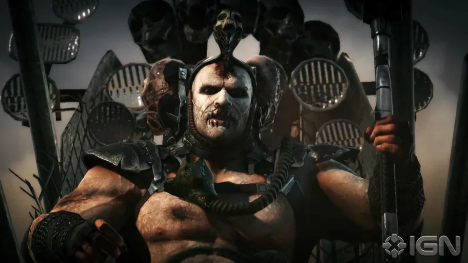 A muscular, heavily armored, and grotesquely scarred video game villain with a skull on his head sits on a throne surrounded…