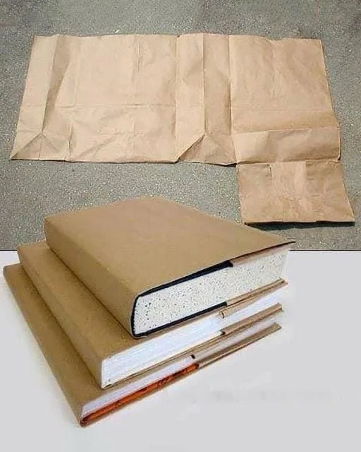 The image shows three thick books with brown paper covers stacked on a white surface, with a large brown paper bag spread…