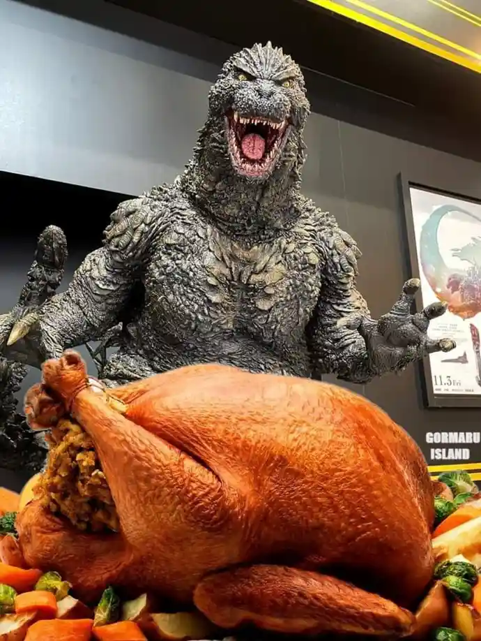 A large, roaring Godzilla statue is positioned behind a giant roasted turkey surrounded by vegetables, creating a surreal…