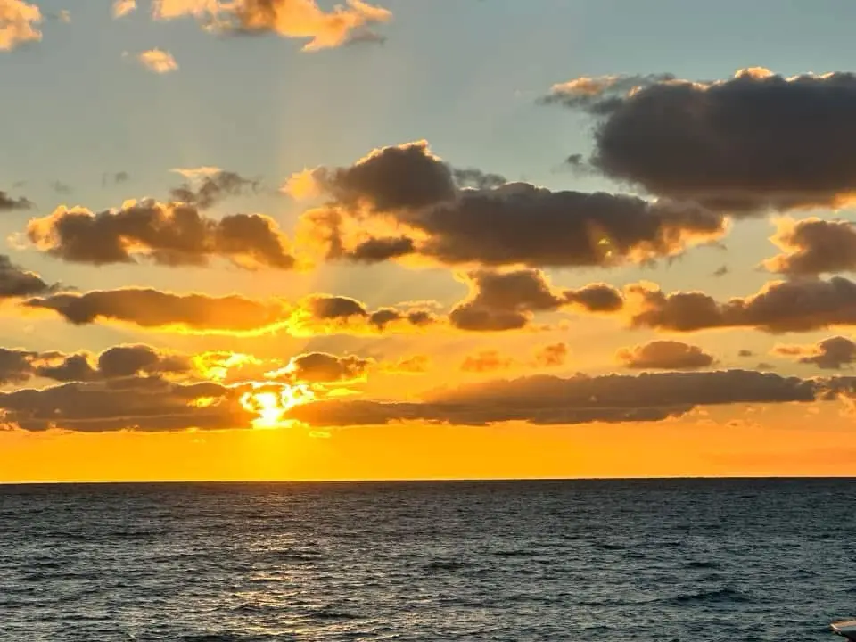 A serene sunset over the ocean with golden-orange clouds and sun rays breaking through, overlaid with the text 'i'm not…
