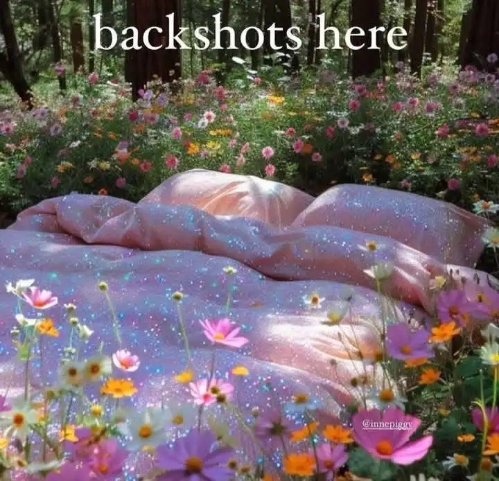 A surreal image shows a large, glittery, pinkish-purple bedspread spread out in a sunlit forest filled with colorful…