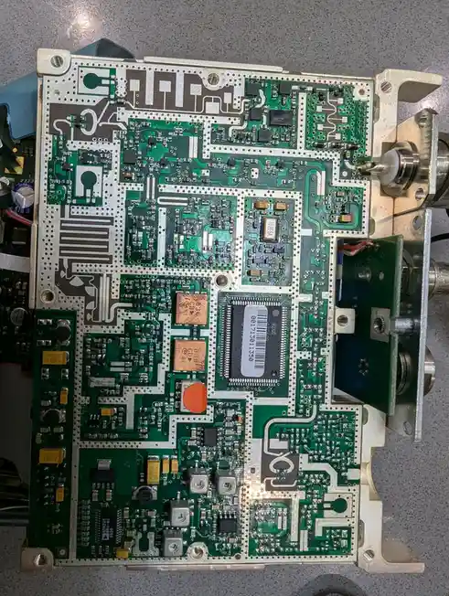 A close-up photo of a complex green circuit board with numerous electronic components, soldered connections, and visible…