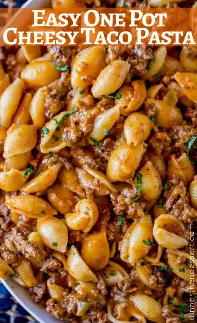 A close-up photo of a dish containing shell pasta mixed with ground meat and a reddish sauce, garnished with chopped green…