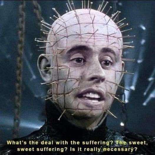 A close-up of the character Pinhead from the Hellraiser franchise, whose bald head is covered in numerous pins arranged in a…