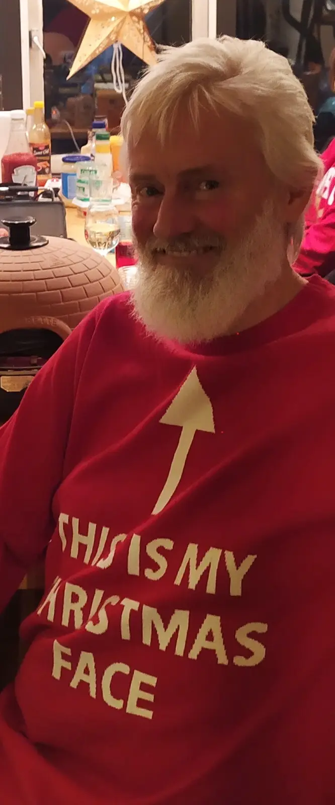 A man with white hair and beard wears a red sweater with a large white arrow pointing upward and the text 'THIS IS MY…