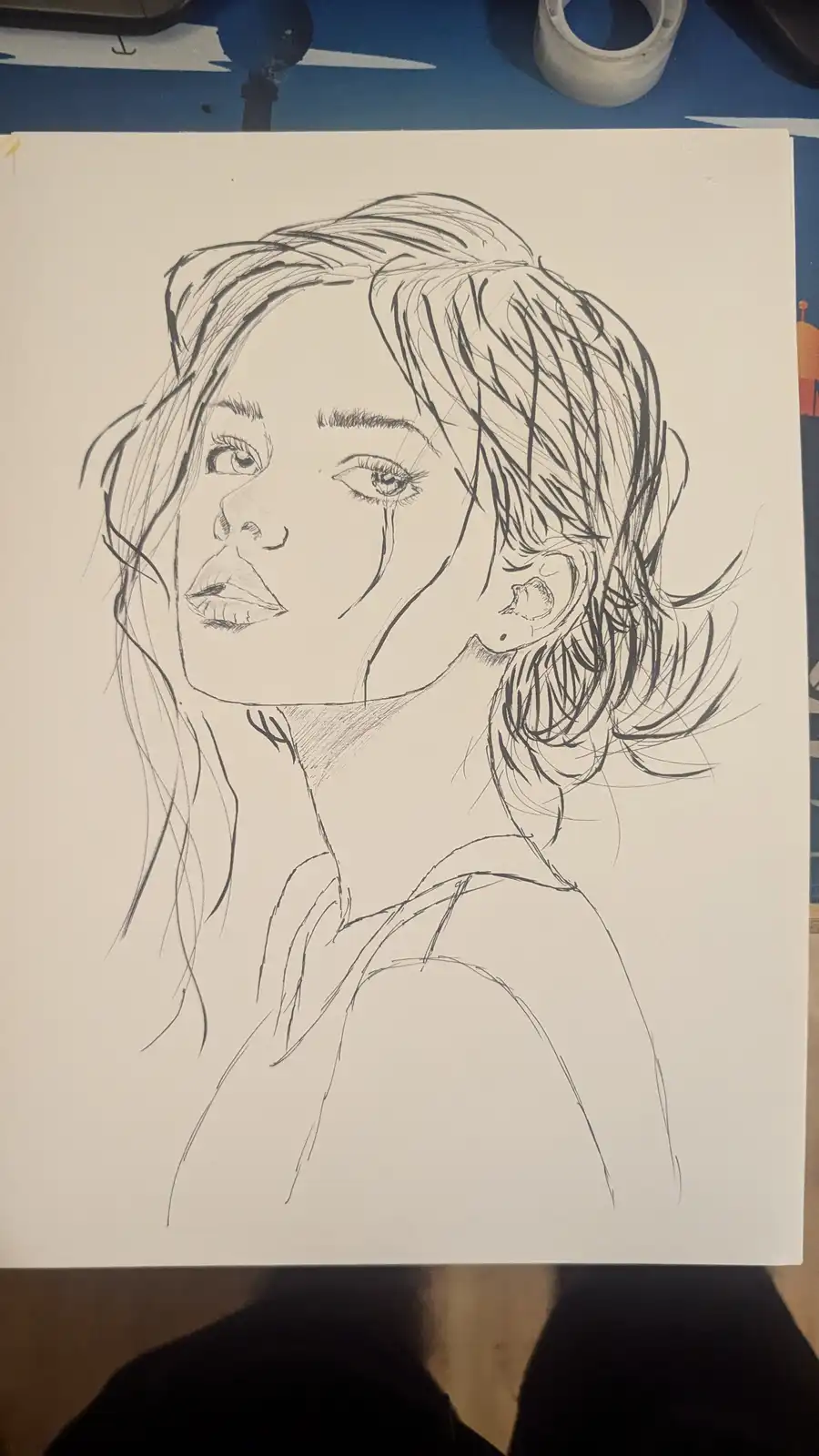 A black-and-white pencil sketch of a woman's face and upper shoulders, drawn on white paper. The drawing shows detailed…