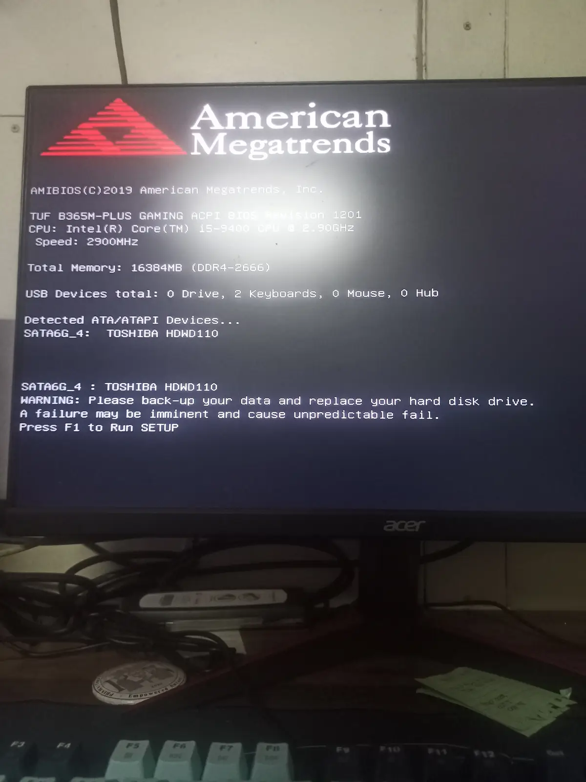 A computer monitor displays an American Megatrends BIOS screen showing system specs and a warning about a Toshiba hard drive…