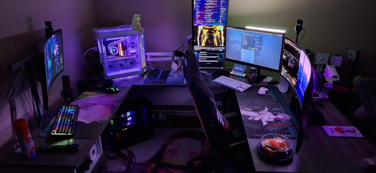 A dimly lit, elaborate gaming and streaming setup with multiple curved monitors, RGB-lit keyboards and a glowing computer…