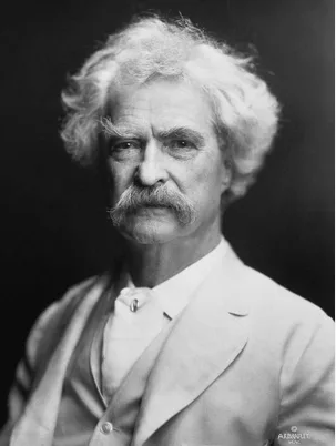 A black-and-white portrait of an older man with white hair and a prominent mustache, wearing a formal suit and bow tie. The…