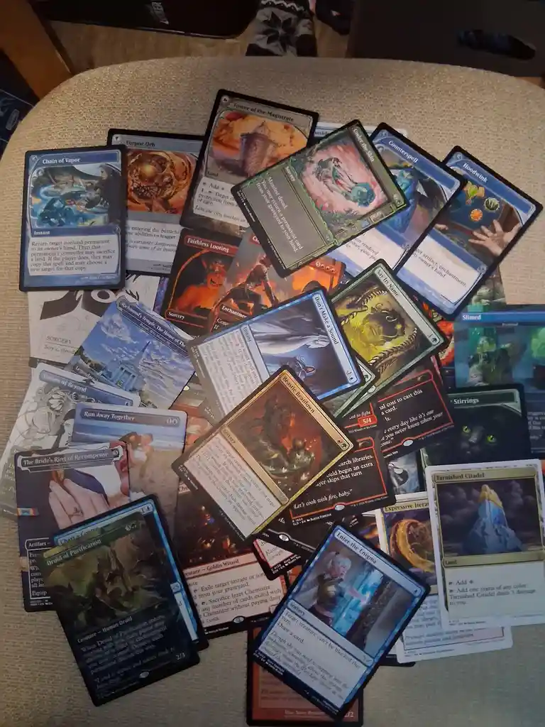 A pile of Magic: The Gathering cards is spread across a table, featuring various spells, creatures, and lands like 'Chain of…
