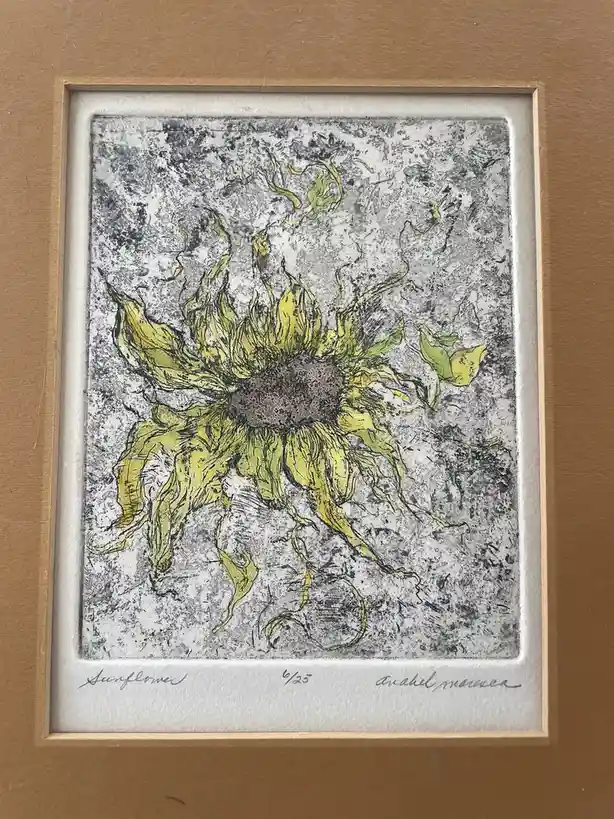 A framed art print depicts a wilting, yellow sunflower with drooping petals against a textured gray background. The artwork…