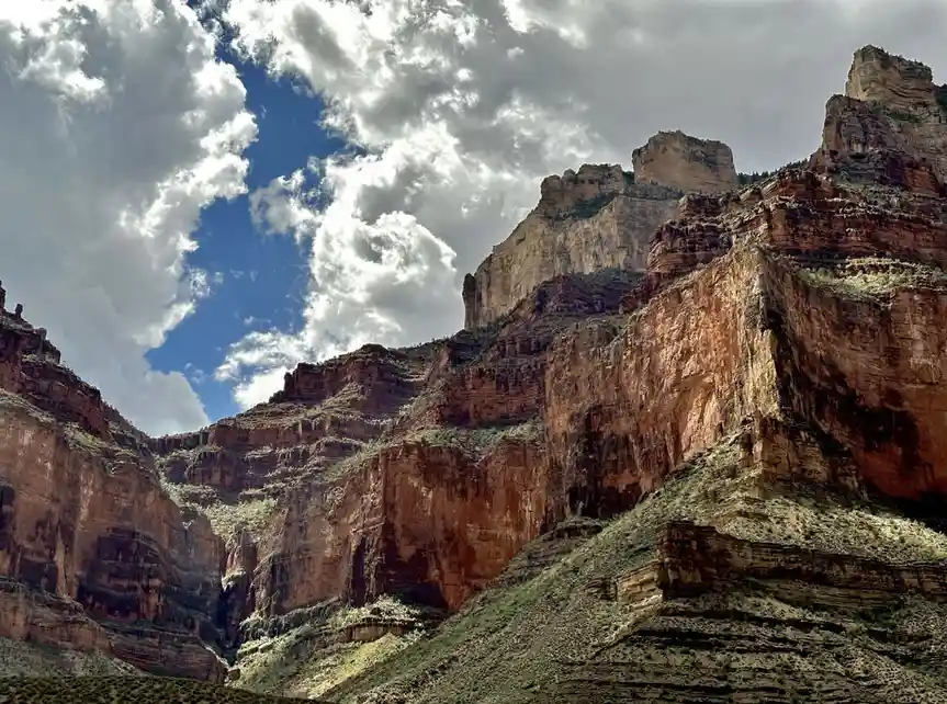 A dramatic landscape photo of layered red rock canyon walls under a partly cloudy blue sky, with overlaid text reading 'i'm…