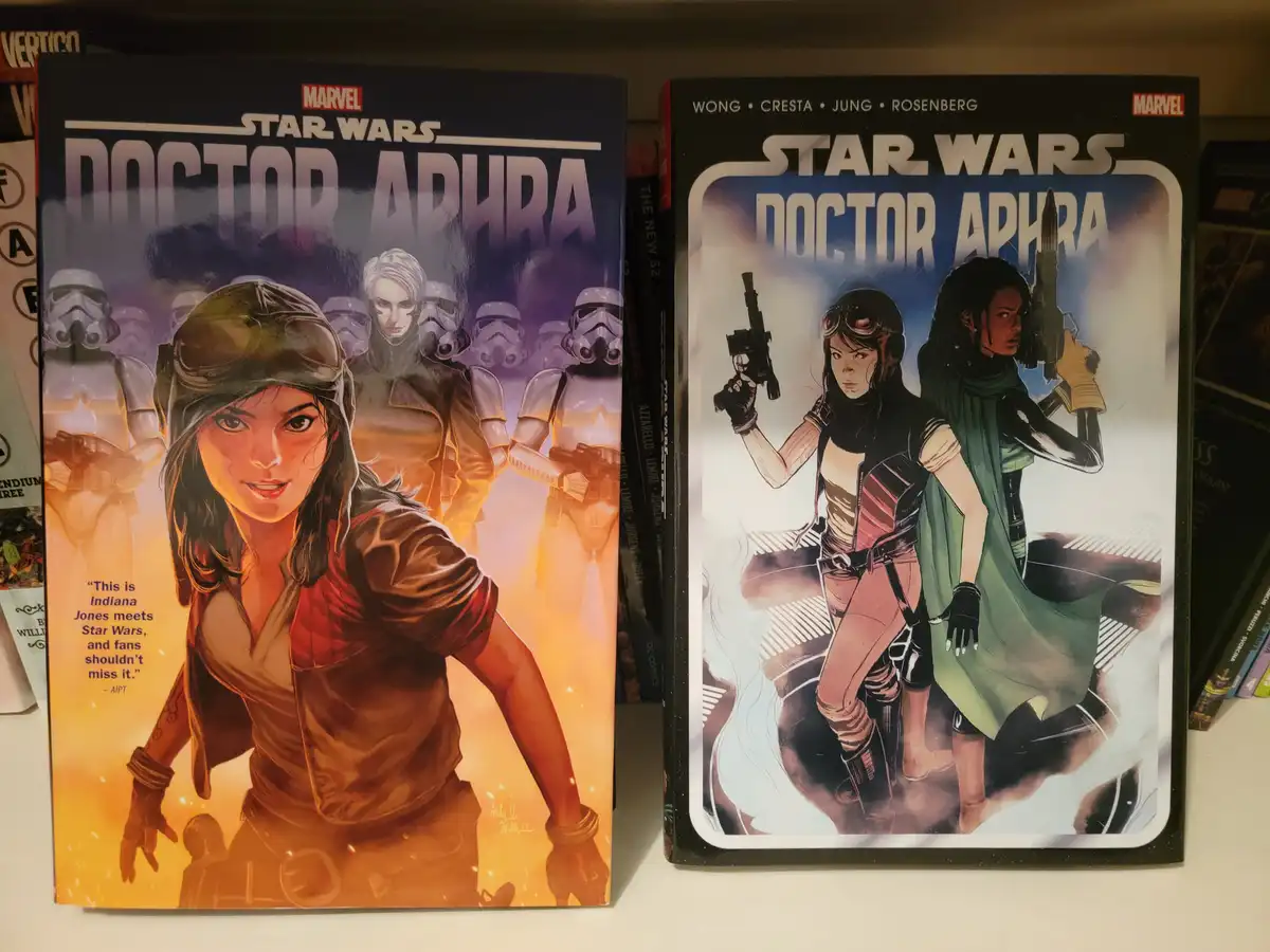 Two 'Star Wars: Doctor Aphra' comic books sit side by side on a shelf. The left cover shows Aphra in a brown jacket with…